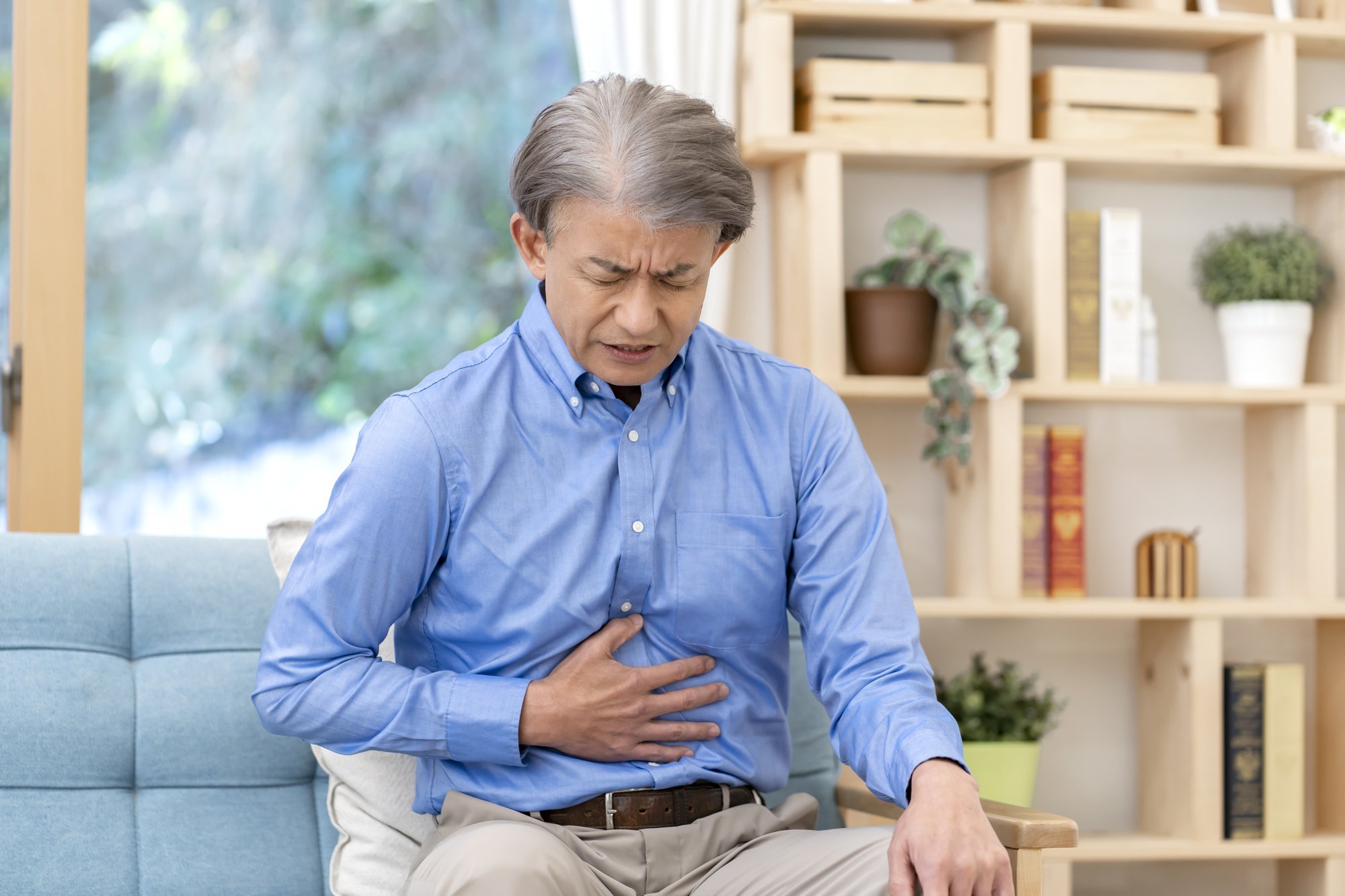 苦しそうな表情で腹部を押さえる中年男性