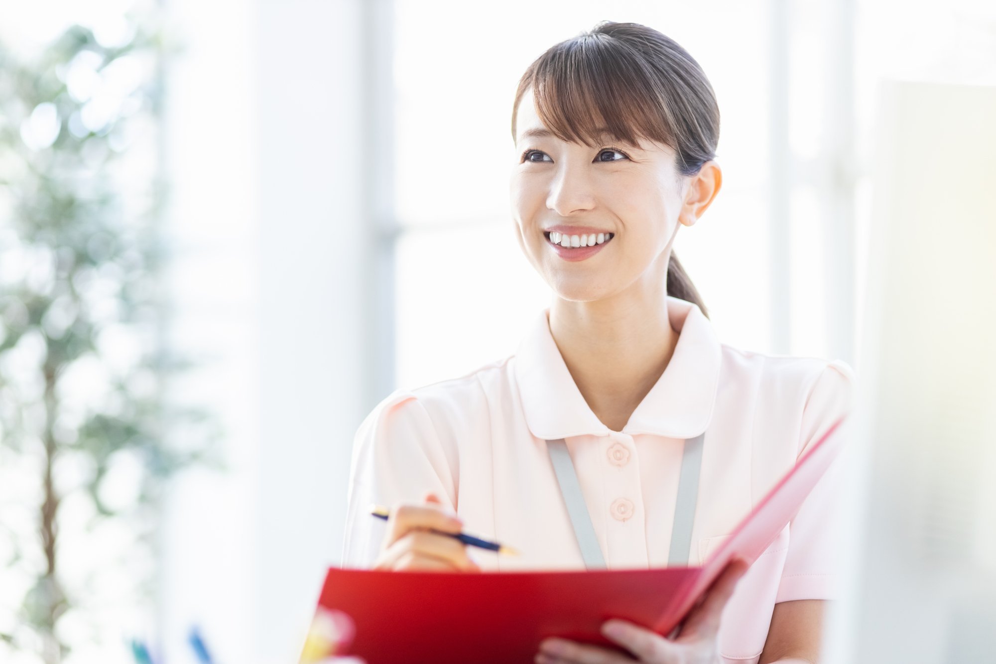 メモを取りながら話を聞いている女性看護師