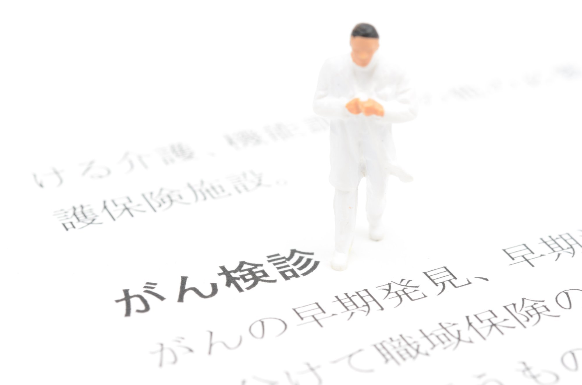 がん検診の文字の横に立っている男性医師の模型