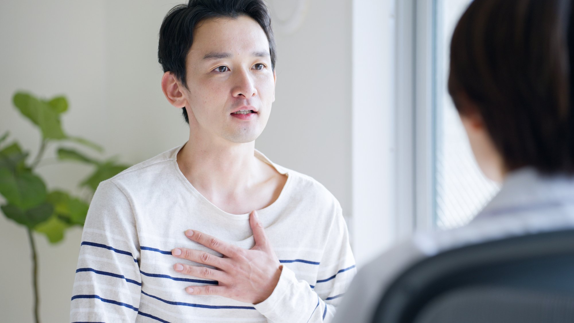 胸に手を当てて医師に相談する男性