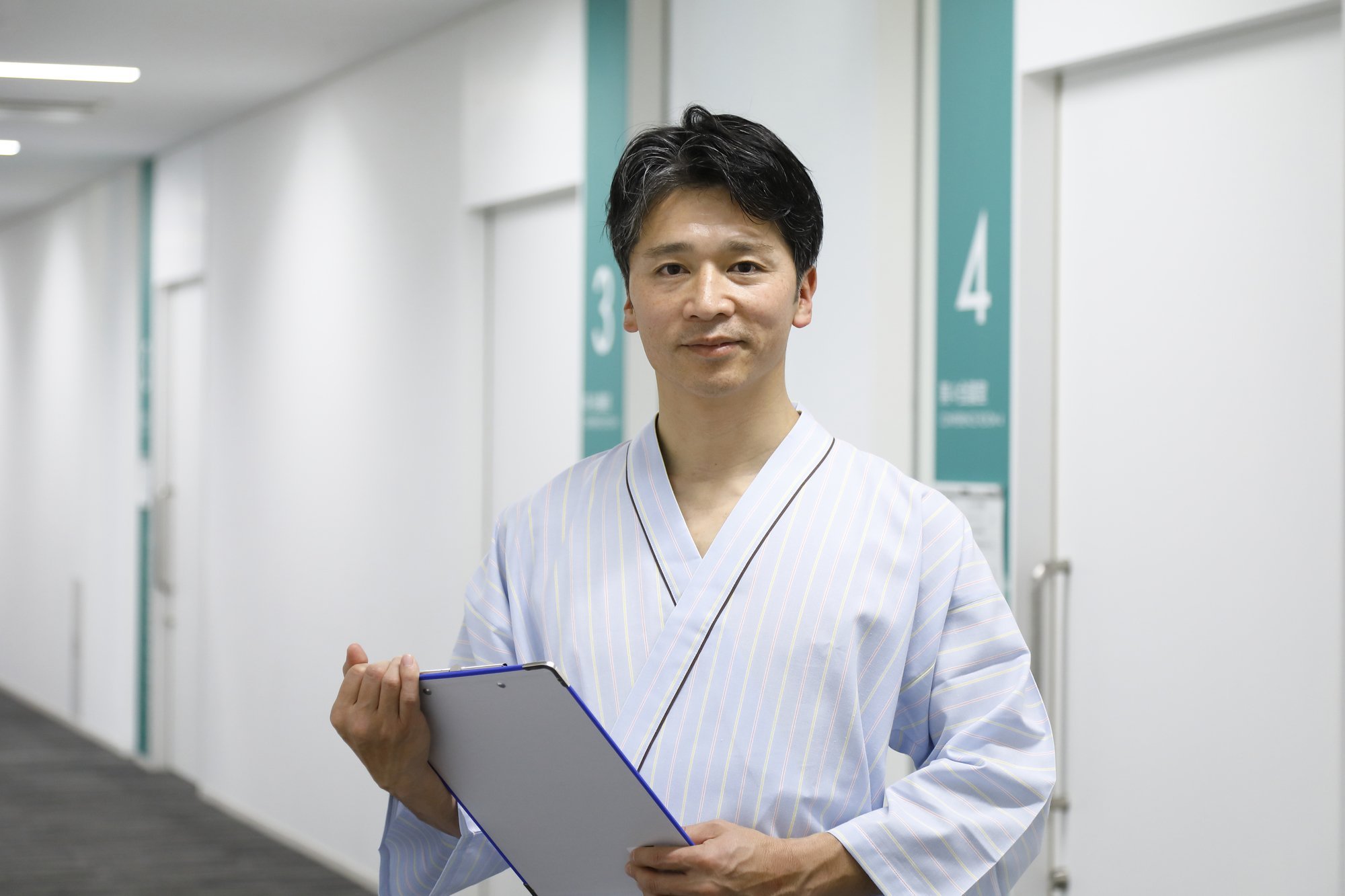 検査着を着用してバインダーを持っている中年男性の患者