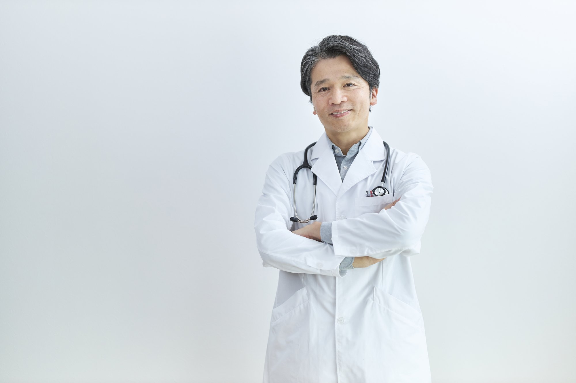 腕を組んで微笑む中年の男性医師