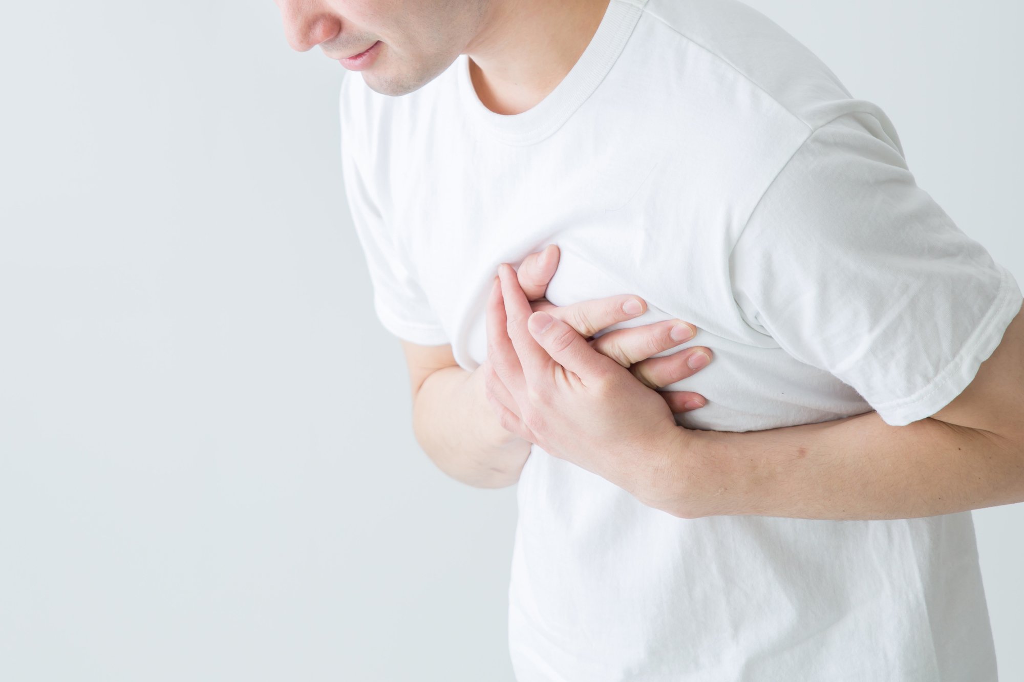 胸の痛みを感じて胸を押さえている男性