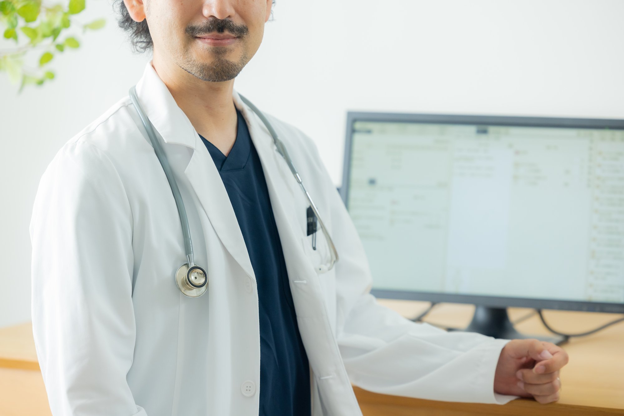 カルテの前で微笑む男性医師